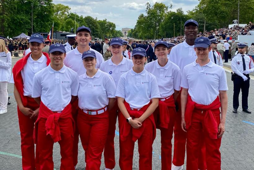 Grupo de jóvenes vestidos de blanco y rojo con el Arco del Triunfo al fondo