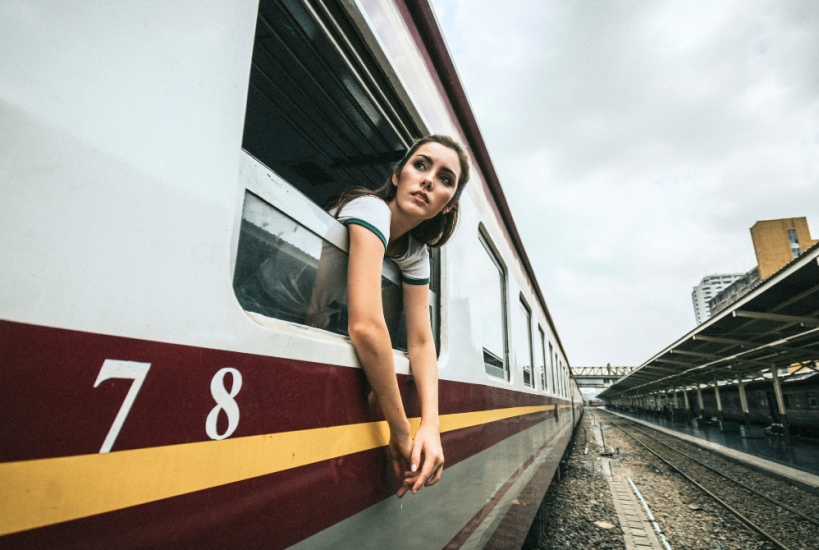 Mujer asomada a la ventanilla de un vagón de tren.