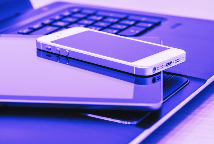 Un móvil y una tablet apilados sobre un portátil abierto
