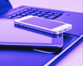 Un móvil y una tablet apilados sobre un portátil abierto